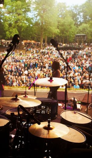 Band, music festival and stage in outdoors, event and party or energy for freedom on vacation. People, back and concert or rave, audio and song for fun crowd and musicians with instruments for show.